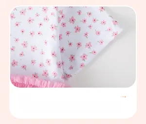 Detail of baby girl floral dress sleeve with pink mesh lace trim and cotton fabric
