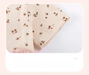 Detail of girl's ribbed cotton sleeve with brown floral print and purple lace trim