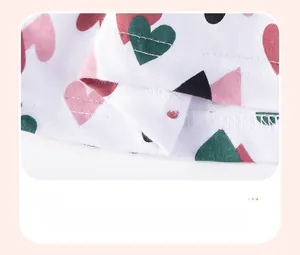 Detail of baby girl dress hem with pink hearts and geometric patterns on white cotton