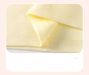 Detailed view of the fine double-stitch hem on a soft yellow cotton girl's t-shirt
