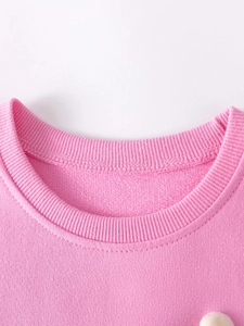 Détail d'une robe rose en coton pour filles avec col rond côtelé et finitions soignées