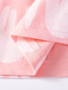 Gros plan d'une robe en coton rose montrant la double couture et l'imprimé blanc artistique