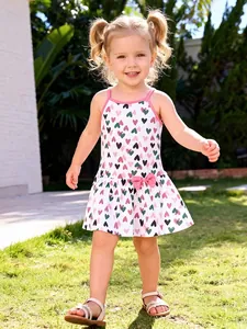 Girl's summer white sundress with colorful heart prints and pink bow detail on waist