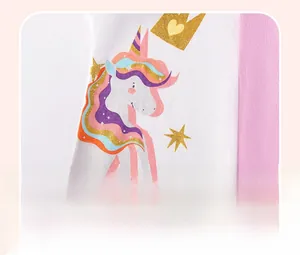 Close-up of girl's cotton dress showing unicorn print with gold glitter crown and stars