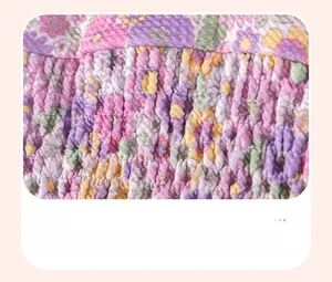 Dettaglio dell'abito floreale da bambina con ricamo a punto smock e piccoli fiori rosa