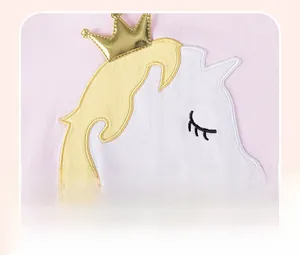 Détail de la broderie appliquée licorne et couronne dorée sur la robe de fille rose
