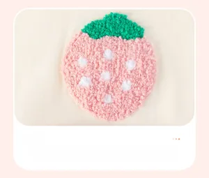 Detail der rosa Erdbeer-Handtuchstickerei auf cremefarbenem Kinderstrickkleid