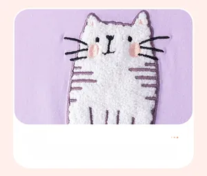 Gros plan d'une broderie bouclée chat sur tissu tricoté violet pour robe de fille