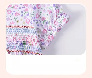 Detail of smocking embroidery and red stitching on a floral cotton dress for girls