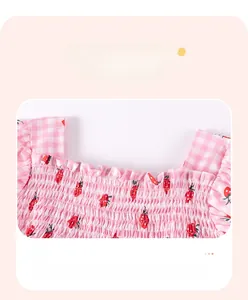 Détail de robe fille à carreaux fraise avec smocks élastiques et décolleté à volants
