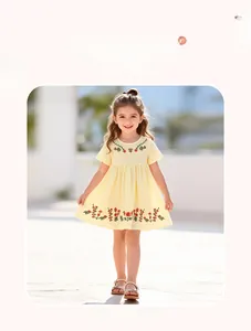 Detailed view of yellow girl's cotton dress featuring floral and leaf embroidery