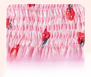 Vue détaillée de la broderie smockée et imprimé fraise sur tissu vichy rose