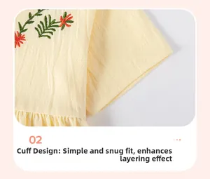 Detail of baby girl dress sleeve featuring delicate orange floral embroidery on yellow fabric