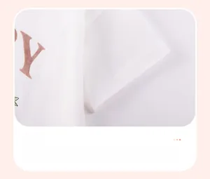 Détail de la manche en coton blanc avec double couture et logo marron sur le t-shirt