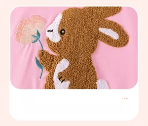 Detail of towel embroidery featuring a cute brown rabbit holding a flower on pink fabric