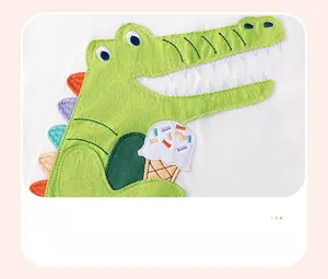 Close-up of green crocodile applique embroidery with colorful ice cream on white cotton fabric