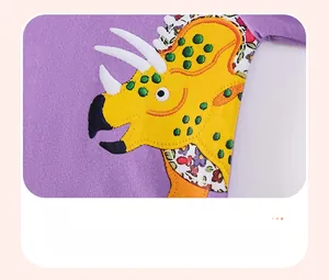Detail van paarse katoenen jurk met triceratops-patch en gebloemde applicaties