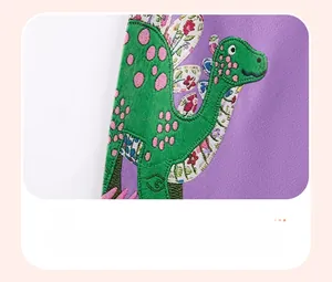 Detail van schattig groen dinosaurusborduurwerk met bloemenstof op paarse meisjesjurk