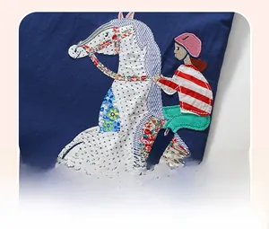 Close-up of girl riding a horse applique with stripe and polka dot patterns on blue dress