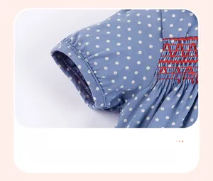 Detail of blue cotton dress sleeve with white polka dots and red smocking cuffs