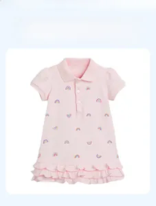 Détail d'une robe polo rose avec broderie arc-en-ciel et ourlet à volants pour fillettes