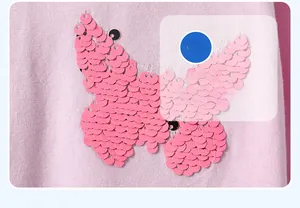 Détail de broderie papillon en paillettes roses sur robe rayée pour enfant