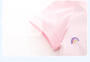 Détail de la manche d'une robe rose en coton avec poignet côtelé et motif arc-en-ciel
