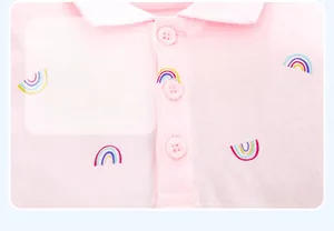 Détail d'une robe polo rose pour fille avec imprimé arc-en-ciel coloré et col à boutons