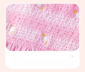 Dettaglio di smock e ricami floreali su un abito rosa a maniche corte per bambina