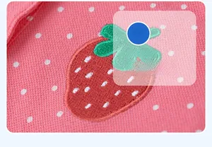 Close-up of pink polka dot cotton mesh fabric featuring a detailed strawberry embroidery