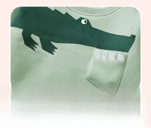 Detail of light green cotton sweatshirt with cartoon crocodile print and 3D teeth embroidery
