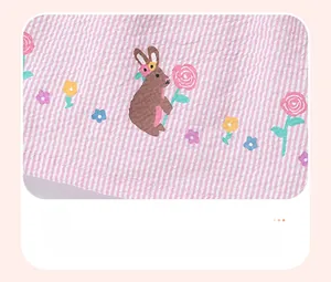 Détail du tissu seersucker à rayures roses avec motifs de lapins et de fleurs