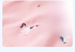 Close-up of pink honeycomb knit fabric featuring colorful unicorn print for girls' dress