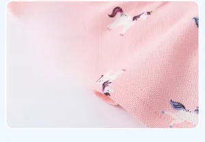 Close-up of pink knit dress hem featuring colorful unicorn prints and fine stitching