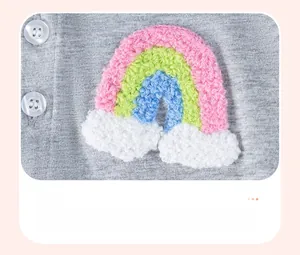 Détail d'une robe en coton pour bébé avec broderie arc-en-ciel et boutons blancs