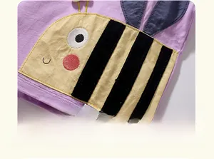 Détail d'une applique d'abeille et broderie sur un t-shirt en coton violet pour fille