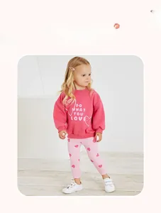 Girl's pink cotton sweatshirt and heart print pants set shown in a model lifestyle pose