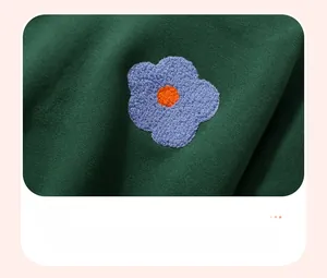 Detail of flower-shaped towel embroidery on a green fleece sweatshirt for girls