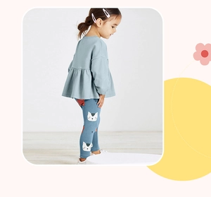 Detail of girls' light blue sweatshirt with ruffle hem and navy cat print leggings
