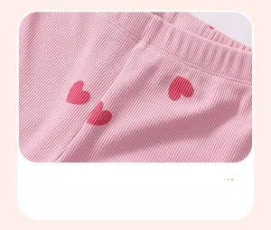 Detail of pink ribbed cotton pants featuring red heart patterns with high-quality printing