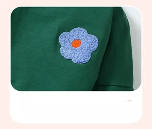 Close-up of light blue towel embroidery flower on dark green knit girls sweatshirt