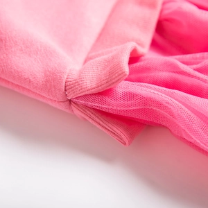 Dettaglio dell'abito in maglia rosa per bambina con polsino in tulle e rete morbida