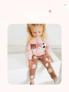 Detail of pink sweatshirt with bear embroidery and brown polka dot pants for girls