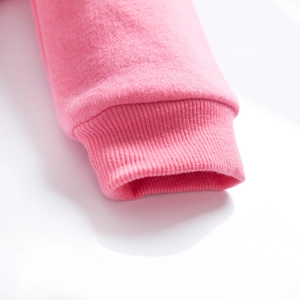 Dettaglio dell'abito rosa con polsini a costine elastici e morbida texture in pile