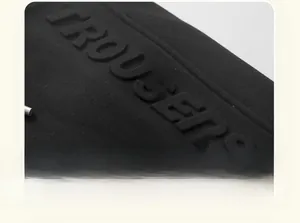 Close-up of thick black fabric featuring 3D embossed TROUSERS lettering detail