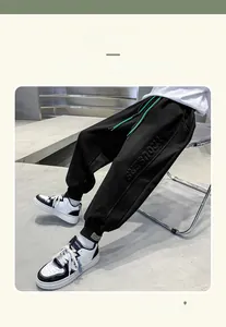 Detail view of boys' black fleece joggers featuring 3D embossed lettering and green drawstring
