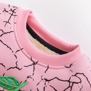Detail of pink fleece sweatshirt showing embroidered green leaf and warm inner lining