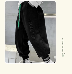 Detail of children's fleece pants featuring 3D embossed trousers text and green drawstring