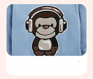 Detail of light blue kid sweater featuring a 3D monkey embroidery with headphones