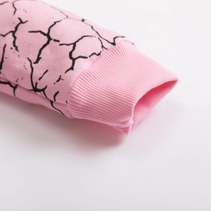 Close-up of pink long-sleeve sweatshirt ribbed cuffs with black lightning pattern